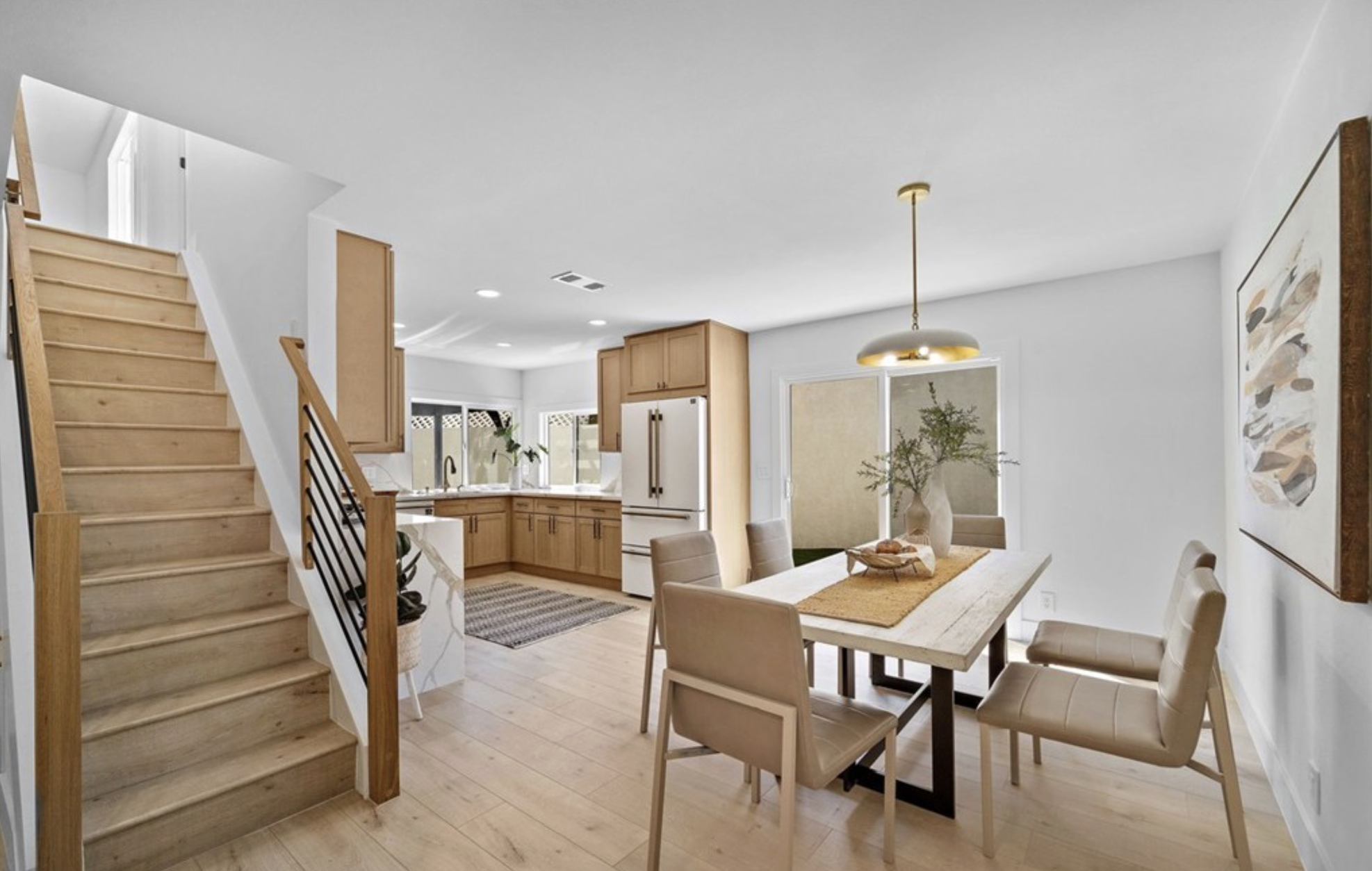 Open dining area with new staircase railings, oak flooring and a view into the remodeled kitchen