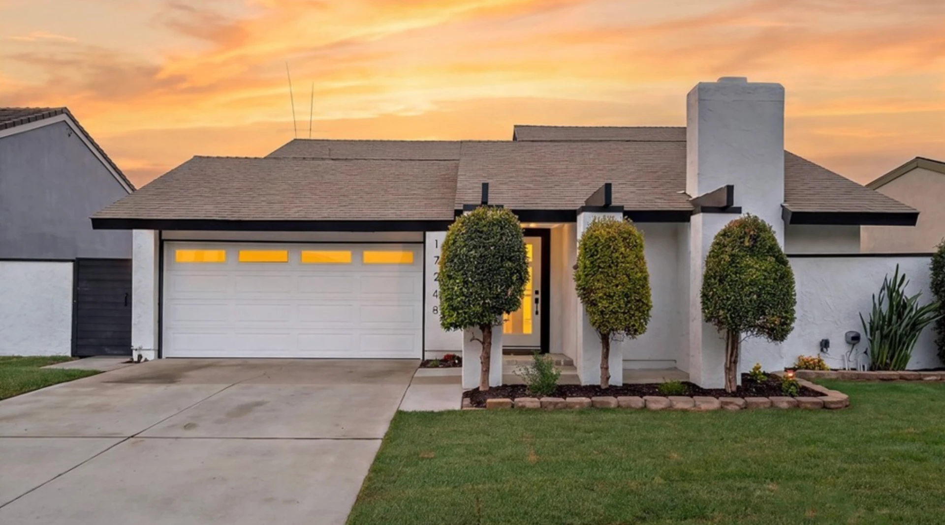 Front exterior of 17248 Reimer Street at dusk with white stucco, dark trim, new landscaping and a two-car garage