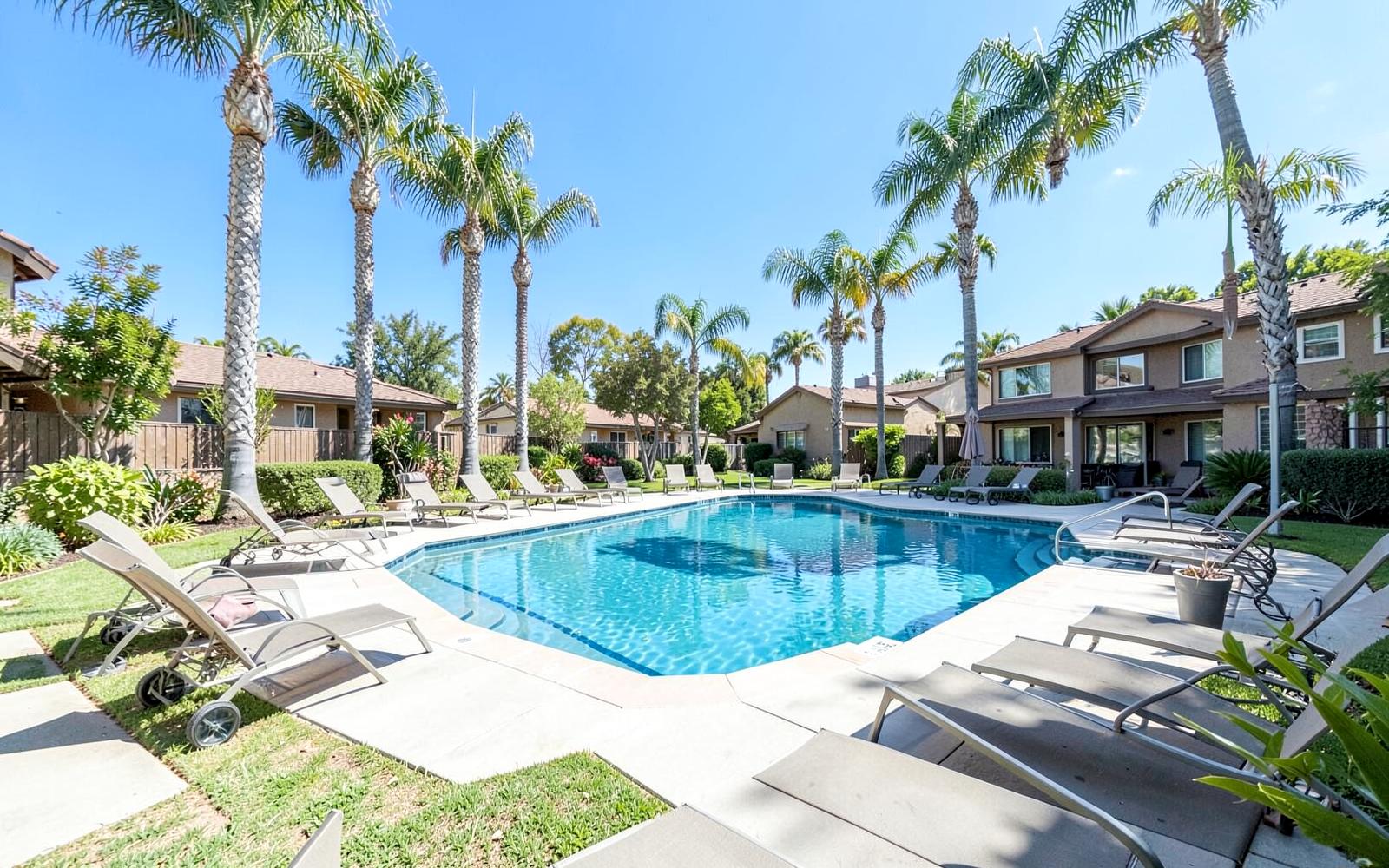 Landscaped community pool surrounded by palm trees in an Orange County HOA community