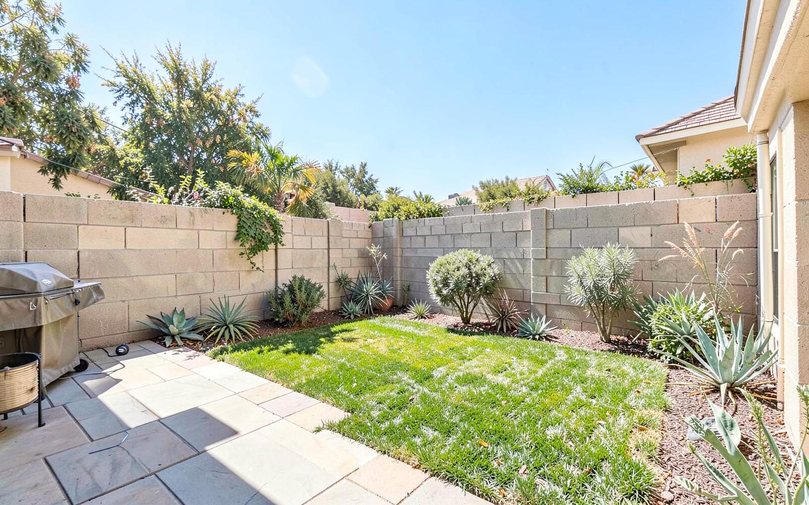 Private Orange County backyard with a paver patio, small lawn and block wall fencing