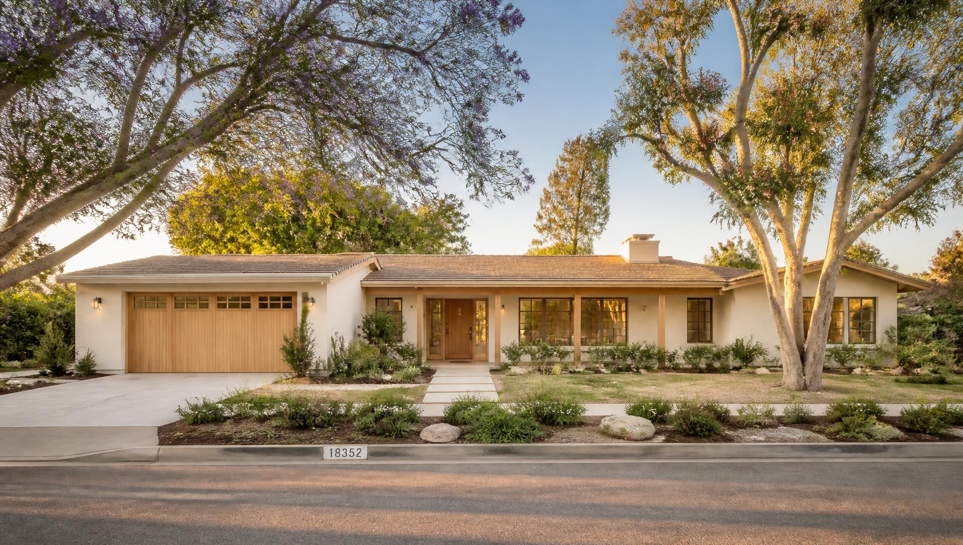 Warm minimalist Tustin ranch home exterior framed by mature trees at golden hour